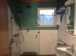 een badkamer met douche, wastafel en raam bij Ferienwohnungen Salmen in Pörtschach am Wörthersee +15 foto's