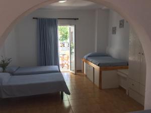 a bedroom with two beds and a door to a patio at Sourmeli Garden Hotel in Mýkonos City