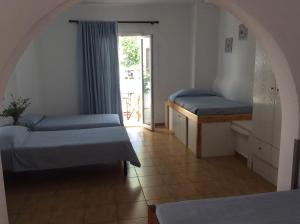 a room with two beds and a door to a patio at Sourmeli Garden Hotel in Mýkonos City