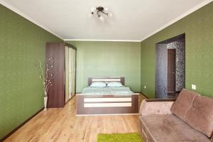 1 dormitorio con paredes verdes, 1 cama y 1 sofá en Apartments Abazhur on Kareltseva 101, en Kurgán