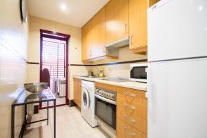 cocina con armarios de madera, lavadora y secadora en Apartamento Green City Deco, en Madrid