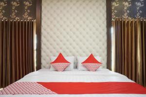 Una cama con almohadas rojas y blancas. en Super OYO 444 Rafitha Homestay en Yogyakarta