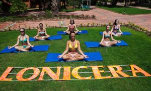 a group of people sitting in a yoga pose on the grass at Lonicera World - Ultra All Inclusive in Avsallar