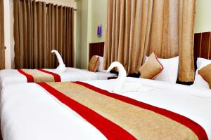 Dos camas en una habitación de hotel con cisnes. en Hotel Guru, en Pokhara