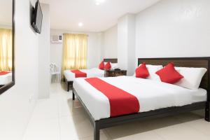 2 camas en una habitación de hotel con almohadas rojas en OYO 152 Sangco Condotel en Manila