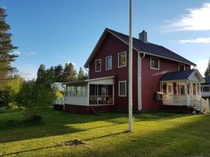 uma casa vermelha com um alpendre e um quintal em Villa Mia em Vidsel