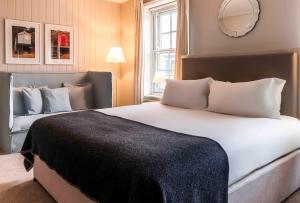 a bedroom with a large white bed and a mirror at The Crown Hotel in Woodbridge