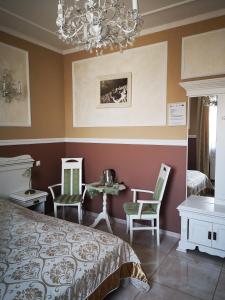 a bedroom with a bed and chairs and a chandelier at Pensjonat Sielec in Sosnowiec