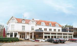 Un edificio blanco con coches aparcados delante. en Fletcher Hotel Apeldoorn, en Apeldoorn