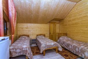 a room with two beds in a wooden cabin at Guesthouse Lyubava in Kamennomostskiy