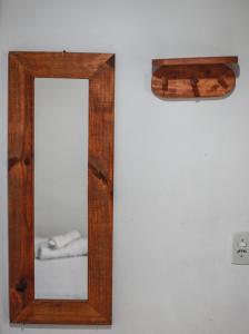 a mirror with a wooden frame on a wall at Pousada e Chalés Itamoara in São Thomé das Letras