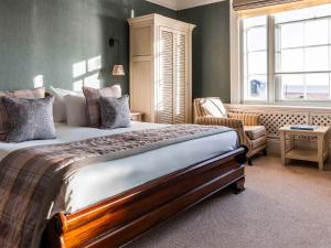 a bedroom with a bed and a chair and a window at The White Lion Hotel in Aldeburgh
