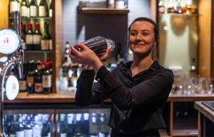 a woman standing behind a bar holding a bottle of wine at The White Lion Hotel in Aldeburgh