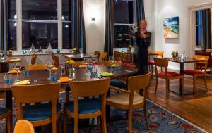 a woman taking a picture of a restaurant with tables at The White Lion Hotel in Aldeburgh