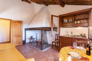 a kitchen with a fireplace and a table with wine glasses at Hotel Casafrassi in Castellina in Chianti