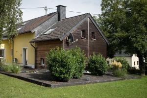 uma casa de madeira com arbustos à frente em Ferienwohnung Moni em Trierweiler