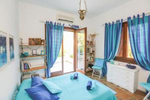 a bedroom with a blue bed and a window at Achladies Beach Apartment in Skiathos