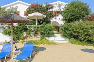 two blue chairs and an umbrella on the beach at Achladies Beach Apartment in Skiathos +8 photos