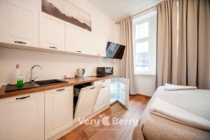 een keuken met witte kasten en een bed in een kamer bij Very Berry - Sniadeckich 1 - Fair Trade Apartments, check in 24h in Poznań