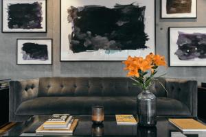 a living room with a couch and a table with orange flowers at Sand Hotel by Keahotels in Reykjavík