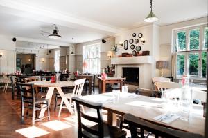 a dining room with tables and chairs and a fireplace at Bel And The Dragon-Churt in Farnham