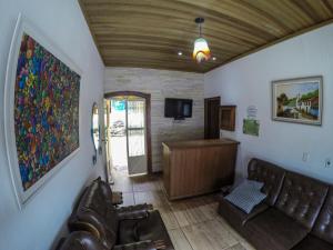 a living room with leather couches and a tv at Pousada e Chalés Itamoara in São Thomé das Letras