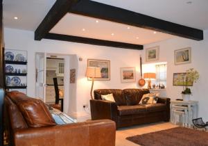 a living room with a leather couch and a table at Justa Cottage in Shaldon