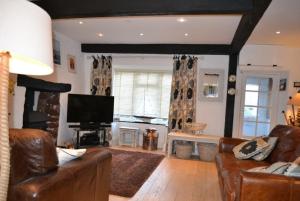 a living room with leather furniture and a television at Justa Cottage in Shaldon +7 photos