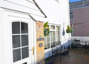 a white house with a patio with a table and chairs at Justa Cottage in Shaldon