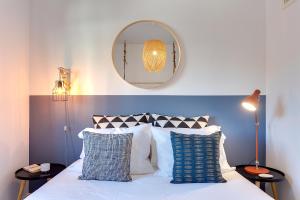 een slaapkamer met een bed met een spiegel en kussens bij DA'HOME - Boavista Brightful Apartment in Porto