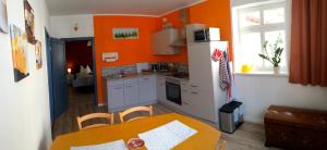 cocina con paredes de color naranja, mesa, mesa y sillas en Ferienwohnungen Am Butterturm, en Bad Langensalza