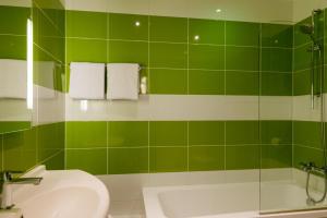 a green tiled bathroom with a sink and a toilet at The Originals City, Hôtel Le Garden, Tours Sud (Inter-Hotel) in Chambray-lès-Tours