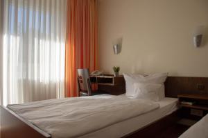 a bedroom with a bed with a desk and a window at Hotel Restaurant Rothkopf in Euskirchen