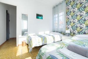 two beds in a bedroom with tropical wallpaper at Fonda Chavarria in Sant Joan Despí