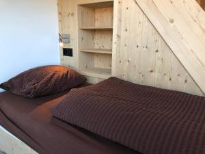 a bed in a bedroom with a wooden wall at Catrina Hostel in Disentis