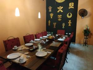 a wooden table with red chairs and a long table with plates at Casa India Catalina in Cartagena de Indias