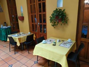 two tables in a restaurant with yellow table cloth at Casa India Catalina in Cartagena de Indias