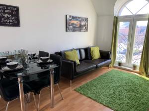 ein Wohnzimmer mit einem schwarzen Sofa und einem Tisch in der Unterkunft Eskdaill Place Apartment in Kettering