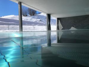 a swimming pool with snow in the background at Catrina Apartments in Disentis