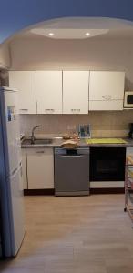 una cucina con armadietti bianchi e frigorifero nero di location saisonnière a Mentone