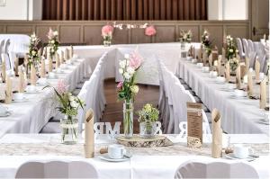 a row of white tables with flowers in vases at Landgasthof Zur Sonne in Fünfstetten