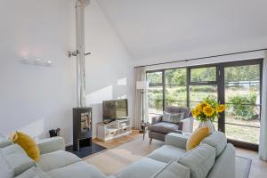 a living room with white furniture and a large window at The Fieldbarns at Bullocks Farm in Bishops Stortford