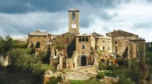 un ancien bâtiment en pierre avec une tour d'horloge sur une colline dans l'établissement "Profumo di Tiglio", à Bagnoregio