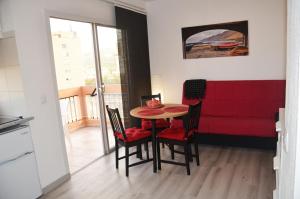 comedor con mesa y sillas y sofá rojo en SunShine Studio, en Puerto de la Cruz