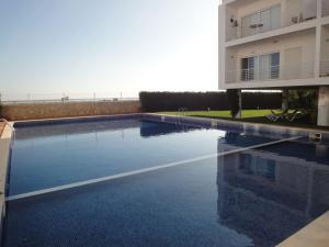 a swimming pool in front of a building at Apartamento Ria Formosa no Mar in Fuzeta
