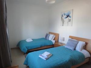 two beds in a hotel room with blue sheets at Apartamento Ria Formosa no Mar in Fuzeta +16 photos