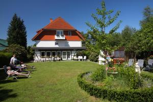een huis met een oranje dak en mensen in een tuin bij Pension Ingrid in Schneverdingen