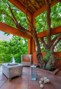 eine Terrasse mit einem Baum, einem Tisch und Stühlen in der Unterkunft The Varos Residences Hotel in Város