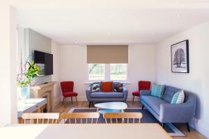 uma sala de estar com dois sofás azuis e cadeiras vermelhas em Longstowe Farmhouse em Long Stowe