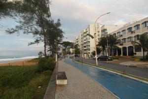 a sidewalk next to a beach with a building at Hotel Bellatrix in Macaé